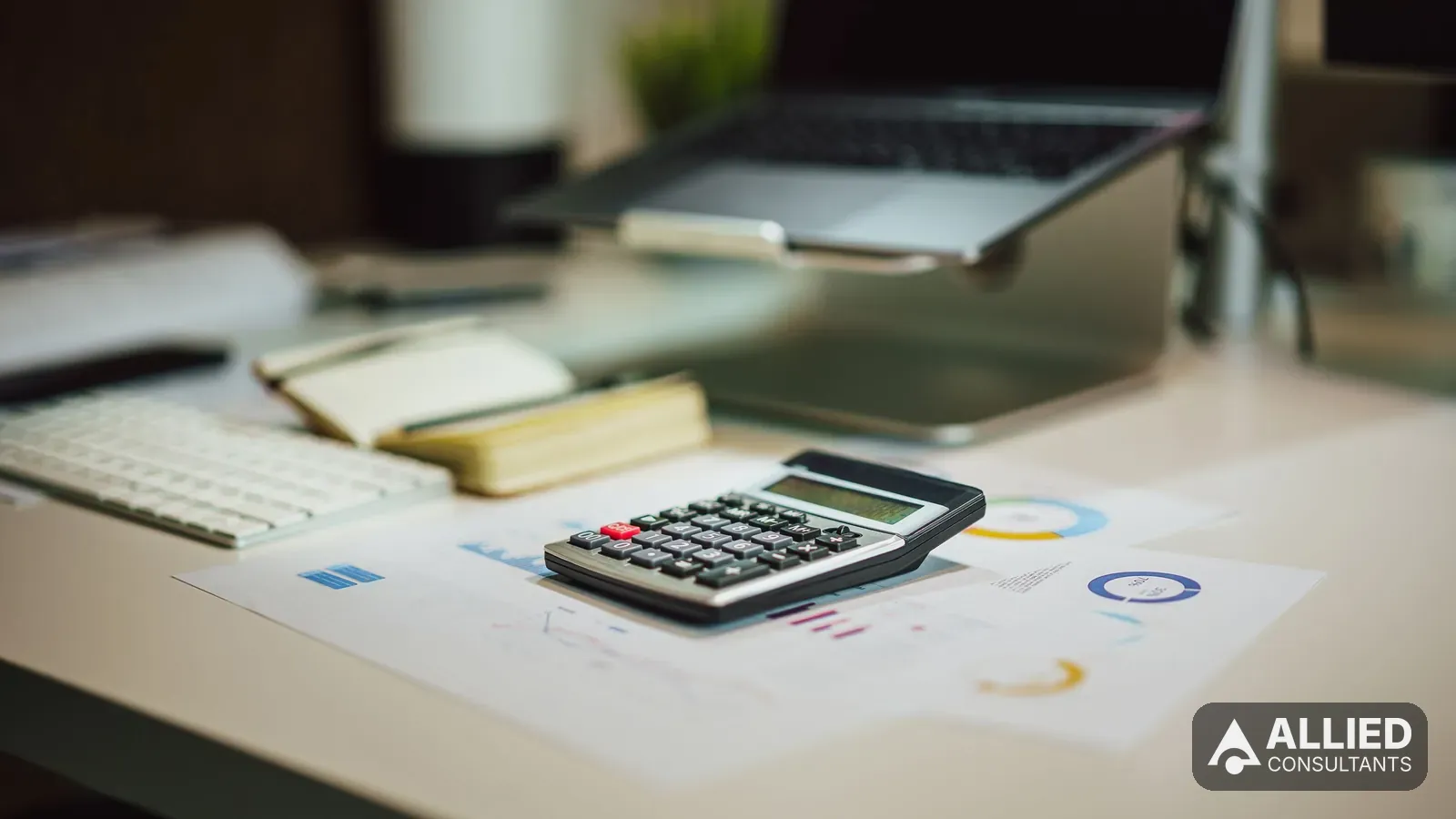 Modern office desk with a laptop, calculator and financial documents used for small business bookkeeping