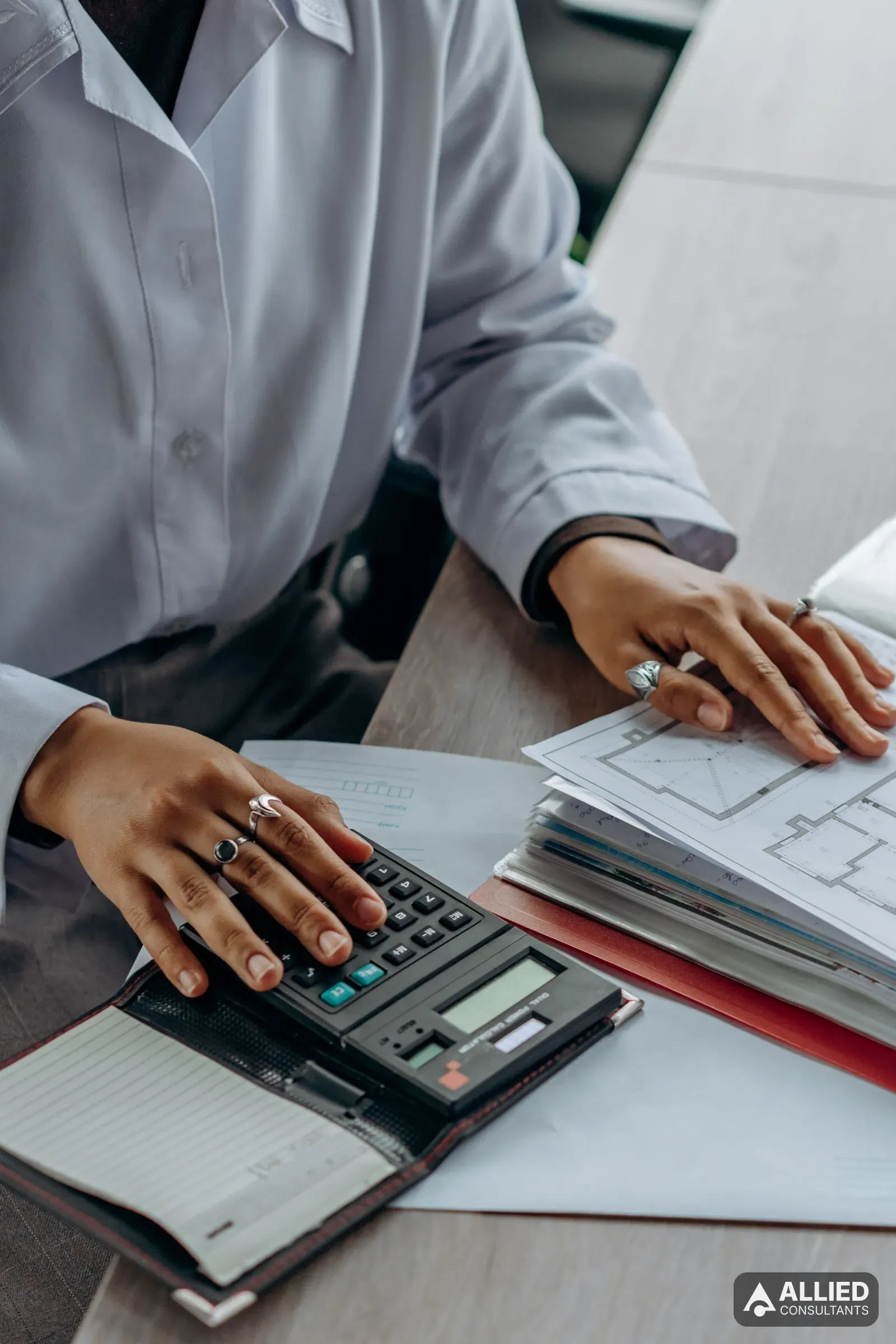 Accountant working through financial documents with a calculator at an office desk