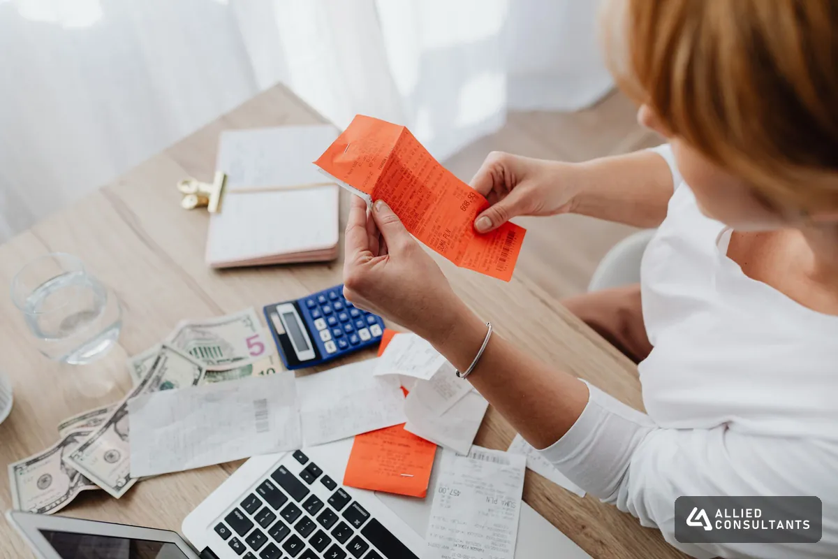 Hands sorting paper receipts and a calculator on a desk during bookkeeping cleanup