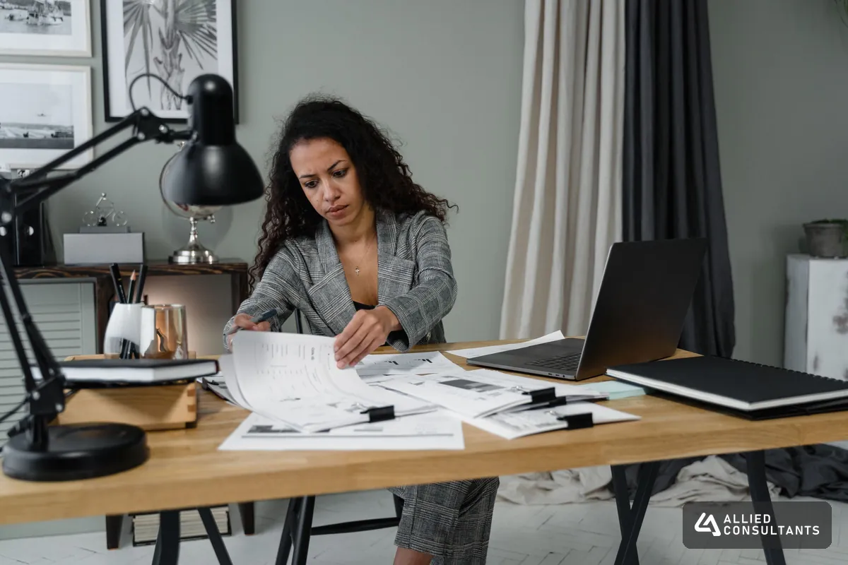 Accountant working through financial papers at an office desk with a laptop