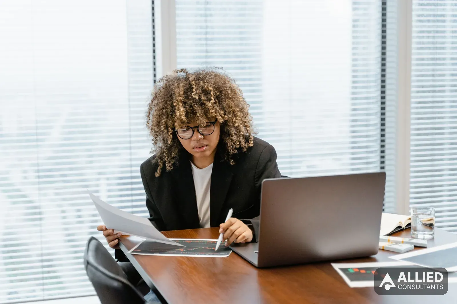 Business professional analyzing financial charts on a laptop at an office desk