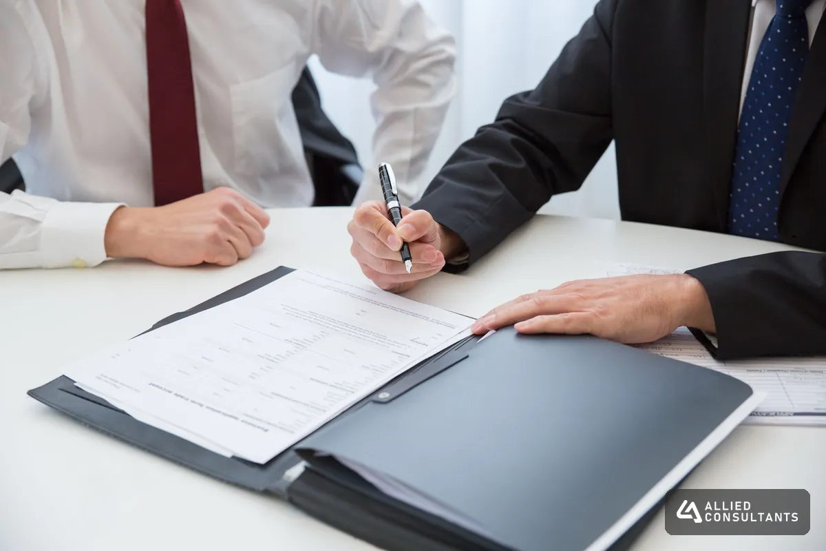 Two professionals reviewing deal documents across a table